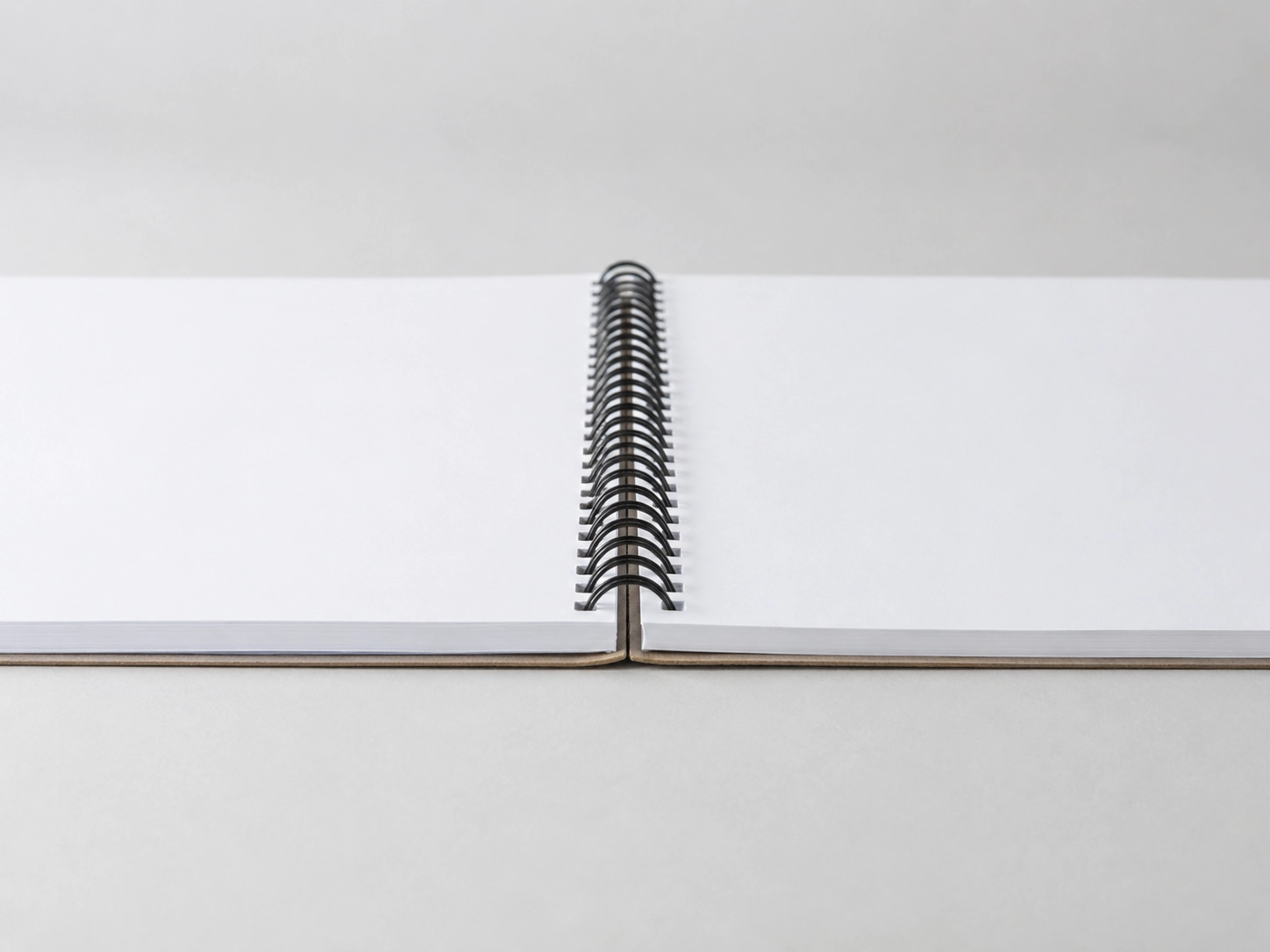 A professional spiral bound book lying open flat on a clean surface, demonstrating the 360-degree rotation and lay-flat capabilities of coil binding